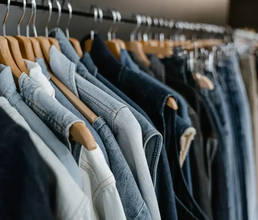 Denim jackets and vests hanging on wooden hangers in a retail rack