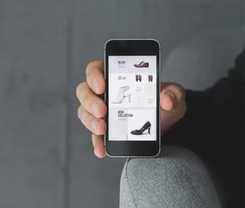 Hand holding a smartphone displaying a fashion ecommerce interface