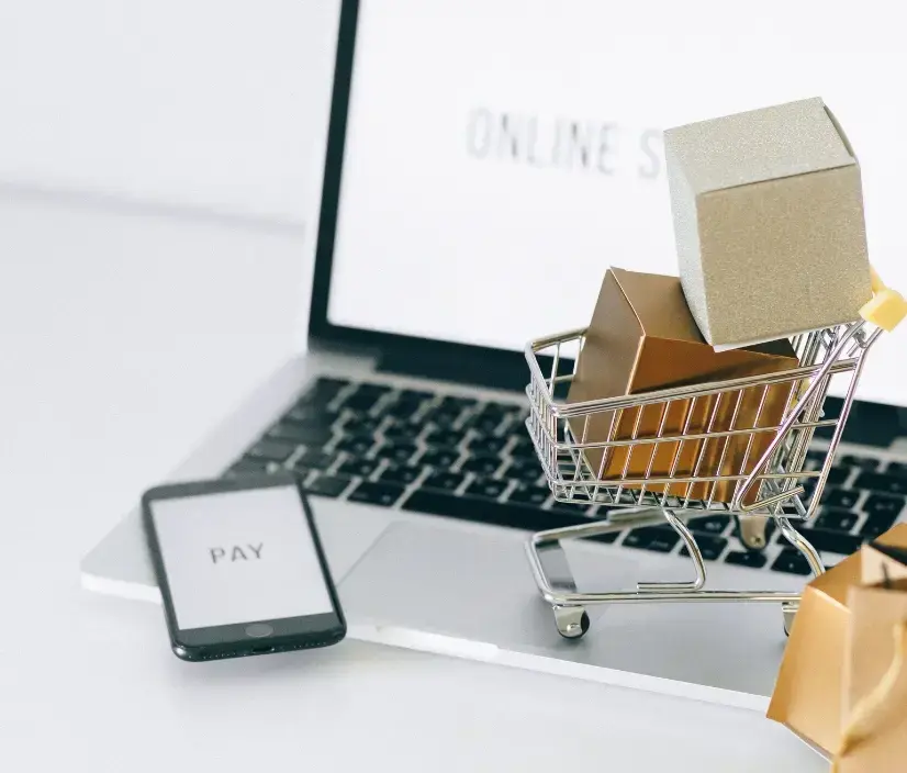 Laptop with miniature shopping cart and smartphone displaying a payment screen