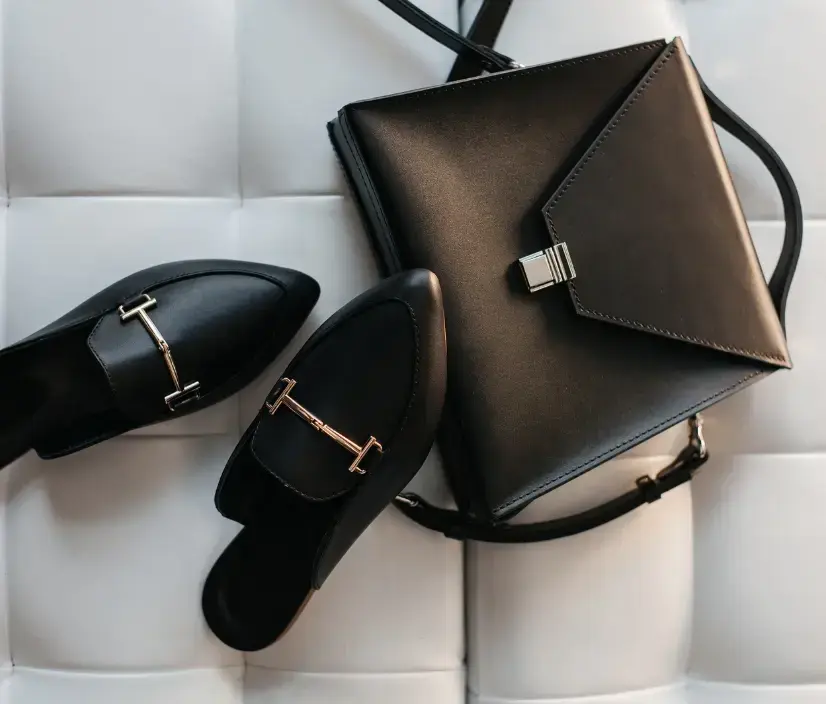 Luxury black leather handbag and loafers on a white tufted surface