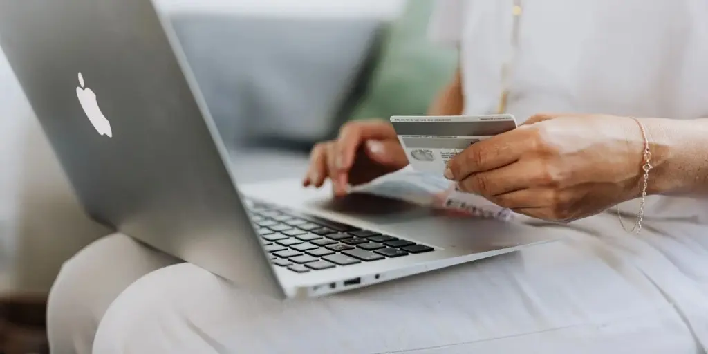 Person holding a credit card over a laptop at the moment of online checkout